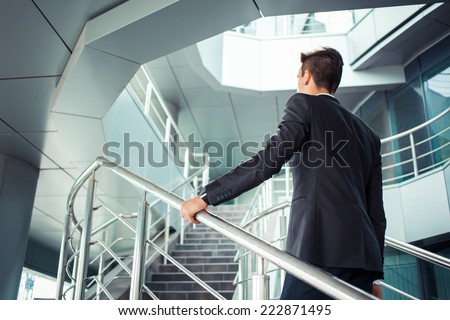 Stylish successful businessman goes up the stairs of the office building