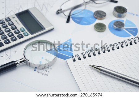 Pen book glasses magnifying glass and calculator on financial chart and graph, accounting background