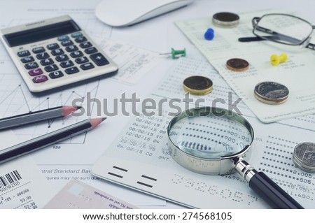 Magnifying glass, pencil, account book, glasses, coin on paper chart, saving concept