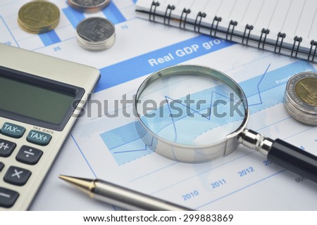 Magnifying glass, pen and calculator on financial chart and graph, accounting background
