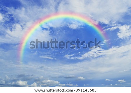 Rainbow with white clouds over blue sky