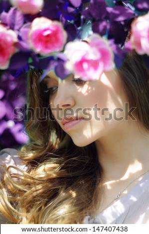 portrait of a beautiful girl in the tea roses and blue leaves