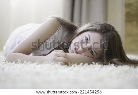 A beautiful young girl laying on the carpet
