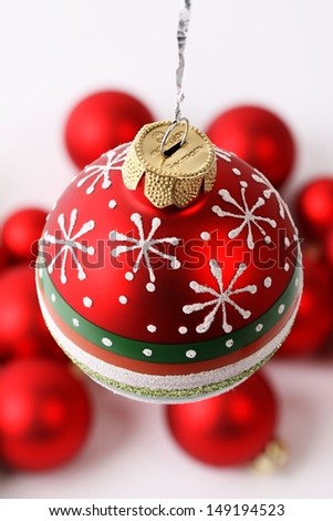 Red joyful Christmas ball with snowflake, dots and stripes in front of red Christmas balls on white background.
