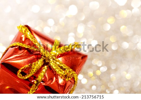 Part of christmas red gift box with yellow bow on glitter silver and gold background