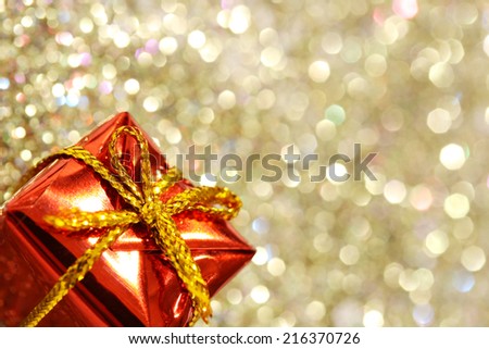 Part of christmas red gift box with yellow bow on glitter silver and gold background