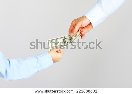 Man hand gives money american hundred dollar bills to boy hand.  Business man give money to business boy. Father and son.