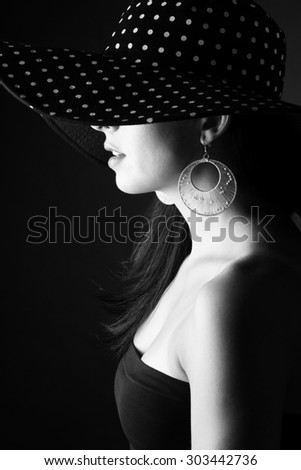 Side face of young woman in black hat with dots and with stylish earring