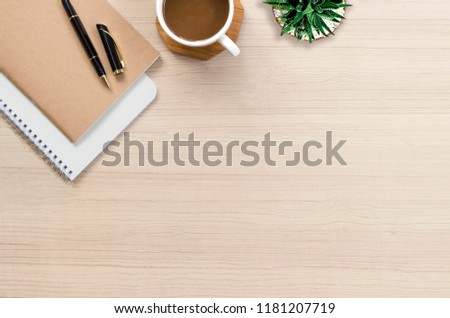 Office desk flat lay with hot coffee, notebook and plant on top view and copy space. Business desk minimal style concept.