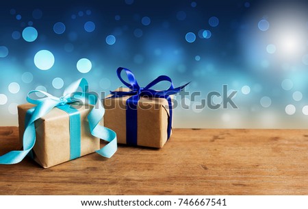 Christmas gift or New Year with blue ribbon on rustic wood table on night blue bokeh background. Tiny handmade gift concept.