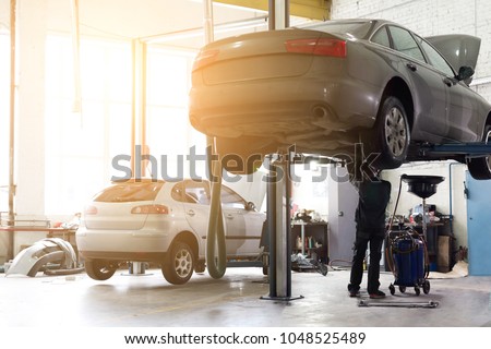 Car service center. Vehicle raised on lift at maintenance station. Auomobile repair and check up