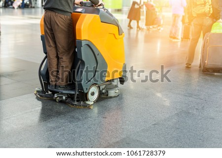 Man driving professional floor cleaning machine at airport or railway station.  Floor care and cleaning service agency