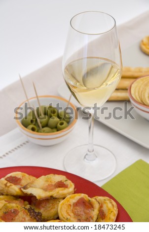 White wine in fine glass with mini pizzas and green olives