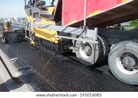 Tracked paver laying fresh asphalt pavement