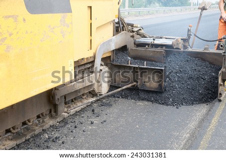 Tracked paver laying fresh asphalt pavement