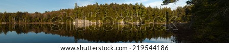 Forest  trees reflecting in calm lake, Frank Lake.  Algonquin Provincial Park, Ontario, Canada