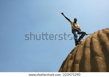MAGA, CAMEROON -CIRCA MAY, 2008 - Man on the top of traditional bulding in open-air museum near Maga Lake, Cameroon