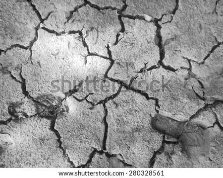 Black and white close up photo of earth cracked because of drought with footsteps photographed from above