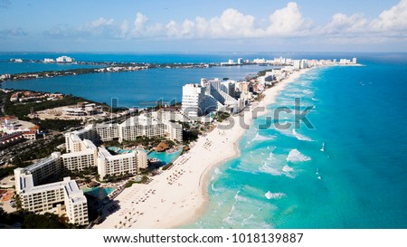 Aerial view of Cancun, Mexico showing luxury resorts and blue turquoise beach. showing people parasailing, swimming and tanning on the beach.