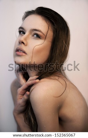 Profile of young woman with beautiful face and eyes, pretty wet hair, crossed hands and drops of water on her face and body, looking up