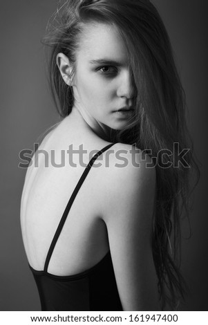 Pretty young woman with beautiful long hair and natural make-up, dressed in black top and looking at camera. Black and White portrait
