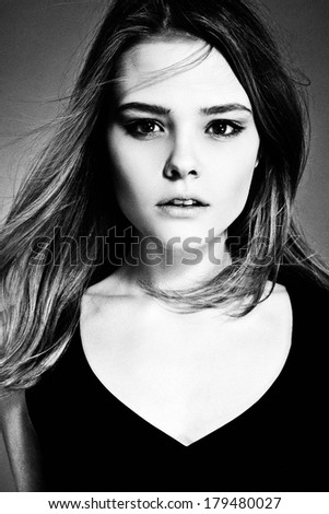 Close up portrait of pretty female with natural make up and long hair, looking at camera. Black and White photo