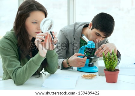 High School students concept. Group of excited students working in science classroom and discovering  biological samples with microscope and magnifying glass
