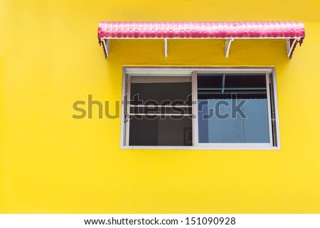 Yellow wall with red awning and windows