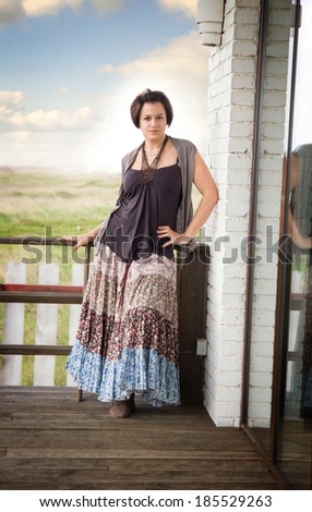 the girl in a long skirt stand on a terrace