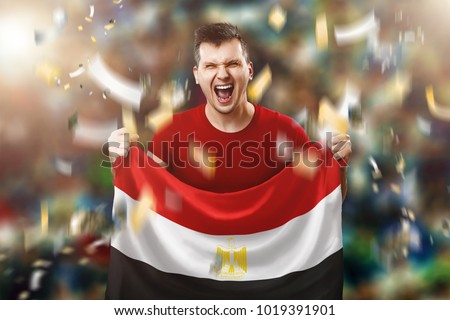 An Egyptian fan, a fan of a man holding the national flag of Egypt in his hands. Soccer fan in the stadium.