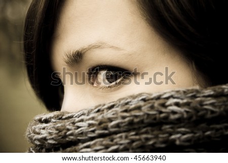 A mysterious portrait of a woman peeking from behind a scarf