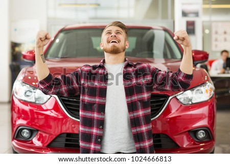 Shot of a young handsome excited man screaming happily with his fists in the air celebrating buying a new car vitory achievement success winner present gift emotions driving transportation auto.