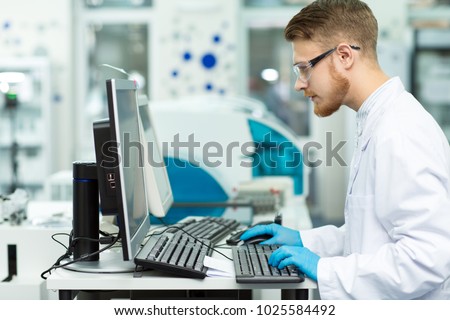 Profile shot of a handsome bearded male young professional scientist working on a computer at the modern laboratory copyspace technology medicine chemistry biology connection researcher.