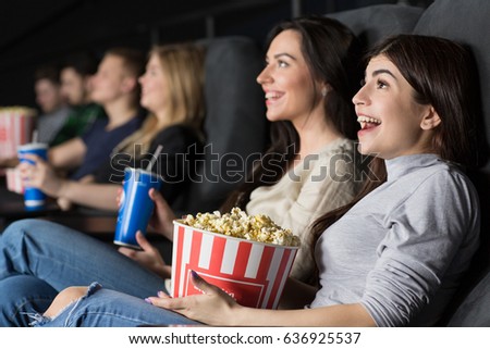Gorgeous young female friends laughing happily enjoying a comedy movie together at the local cinema spending their weekend together copyspace friendship people youth fun entertainment movies industry