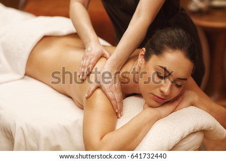 Gorgeous relaxed woman lying with her eyes closed enjoying body massage at spa center professional masseur masseuse massaging relaxing therapy beauty recreation wellness wellbeing health vitality