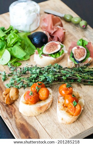 Finger food crostini bites with prosciutto, figs, goat cheese and arugula