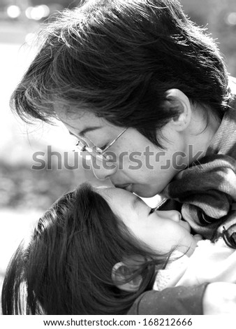 Mother kissing daughter , black and white
