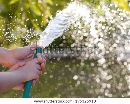 Hands of mother and child Help plants. watering plants in garden