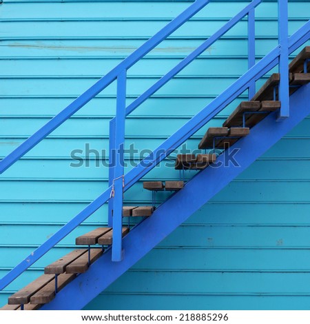 Wooden staircase on blue wooden background.