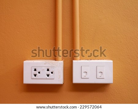 Phone connector and electric plug on orange wall background