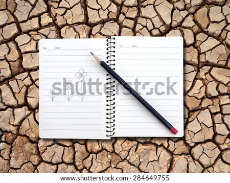 Notebook and pencil draw flowers on drought land background