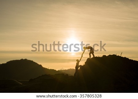 Silhouette of helping hand on mountains in sunset background.