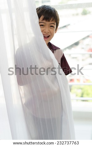Little boy opening the door curtain