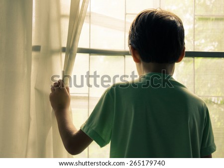 Little boy standing behind the window vintage