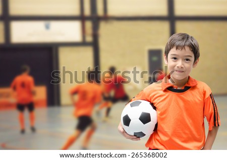 Little boy holding football in gym