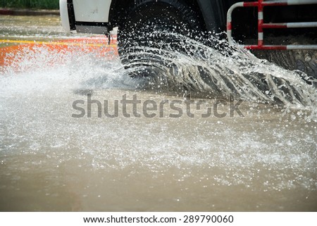 Car's wheels ride on water splashing on the road