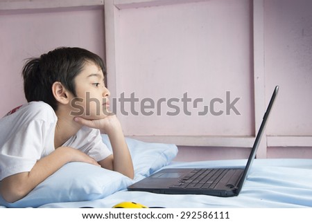 Little boy using notebook laptop in the bedroom