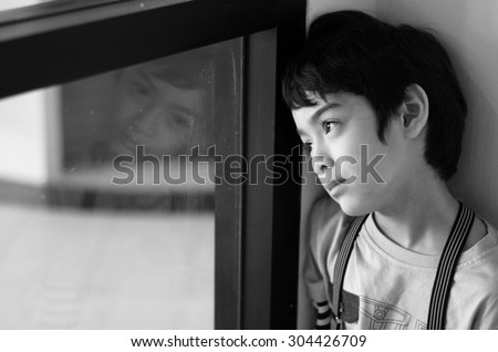 Little boy standing behind the window black and white