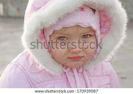 portrait of a little girl close up outdoor in a pink colored winter coat with fur hood on