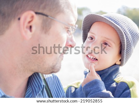 son and father looking each other eyes closeup outdoor